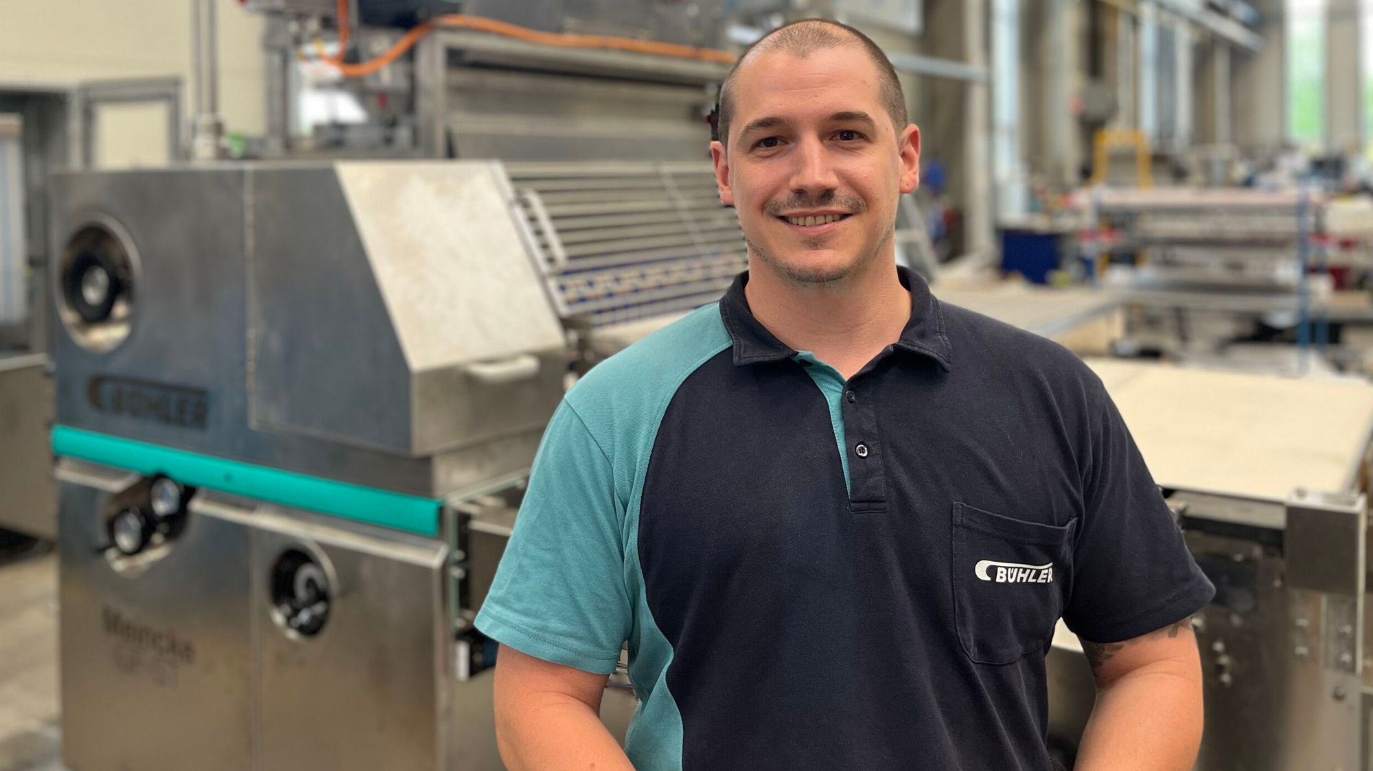 A Bühler employee standing in front of a cracker machine.