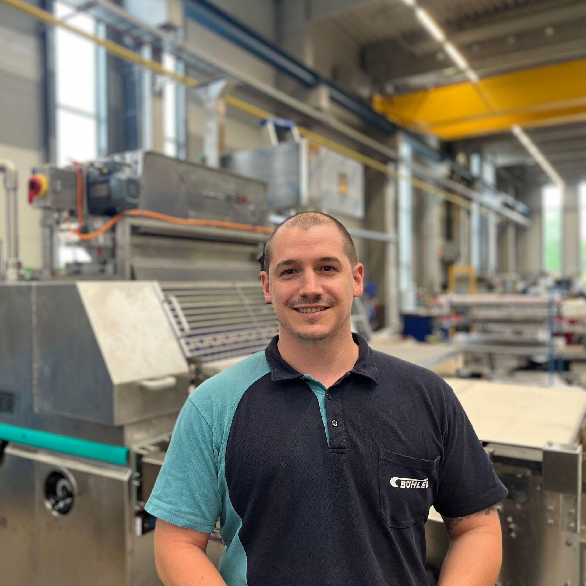 A Bühler employee standing in front of a cracker machine.